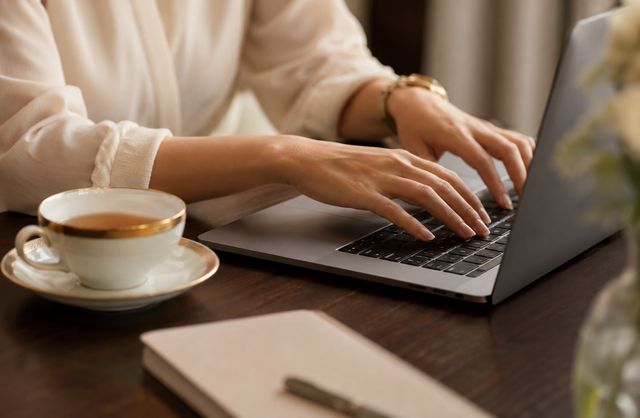 Hands typing on a laptop during digital media research and writing