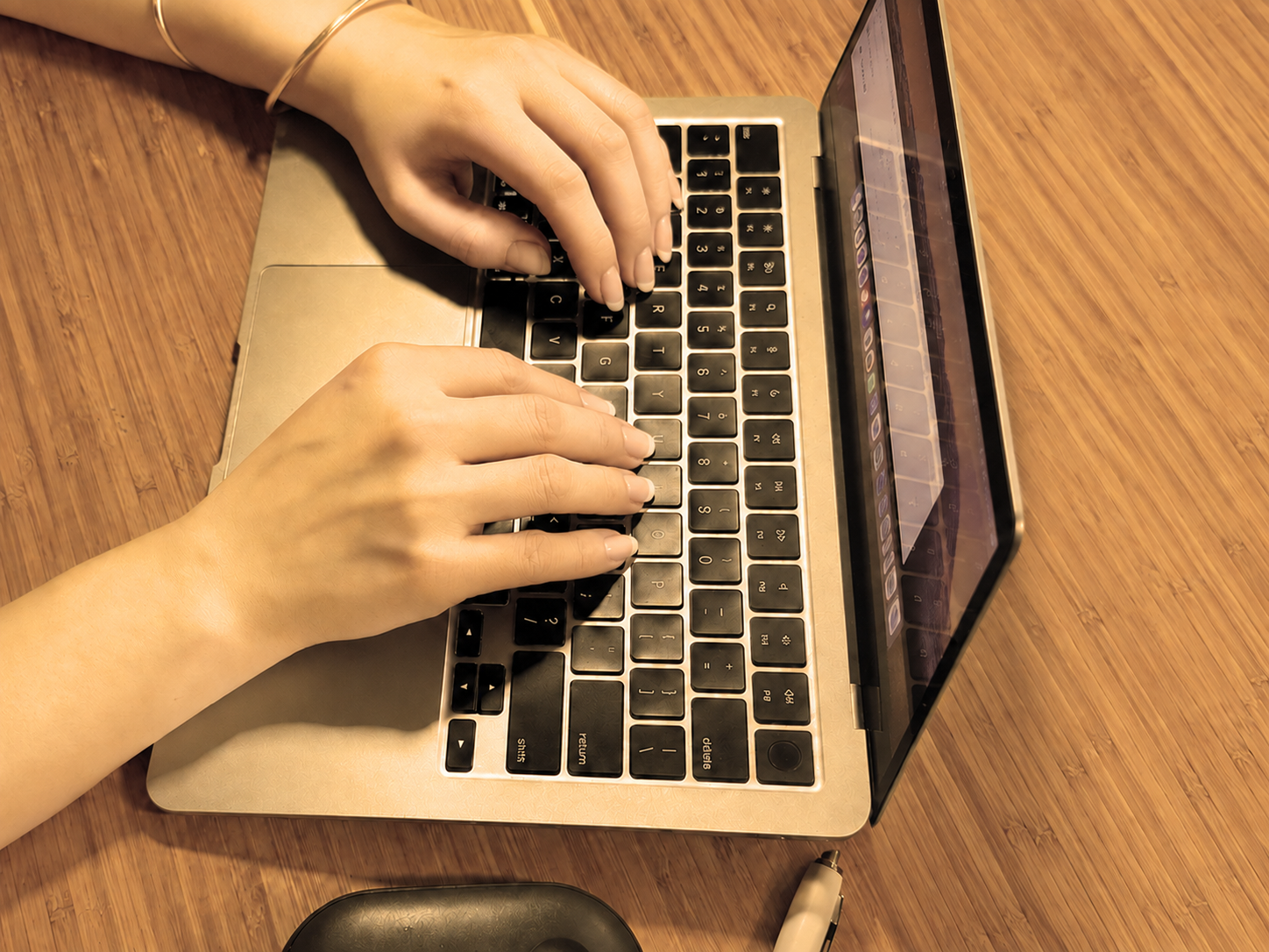 Close-up of hands typing on a laptop keyboard.